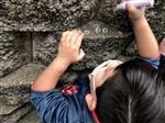 Student using chalk to draw on a rock retaining wall