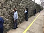 Student spaced out along rock retaining wall using chalk to draw