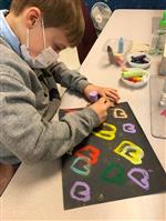 Boy drawing colorful hearts on paper